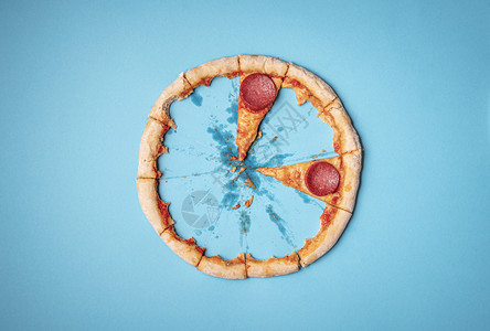 披萨辣椒最后两片和披萨皮壳结剩菜蓝底上面是圆披萨皮壳和沙拉米面片快餐图片