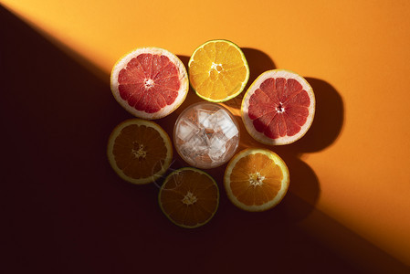 柑橘水果半切成冰块在橙色底的玻璃中切成冰块在阳光下切成冰块准备寒冷的夏季鸡尾酒概念制作热带饮料图片