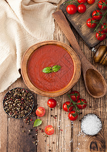 木制番茄汤板勺子胡椒和木制板的厨房布料以及生番茄图片