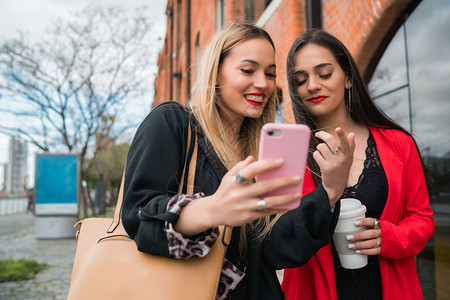 两位年轻朋友在街上户外使用手机图片