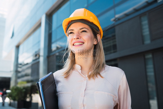身戴黄头盔和户外站立的女专业建筑师肖像工程和建筑概念图片