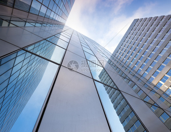 现代办公大楼的玻璃面罩和蓝色天空云的反射图片