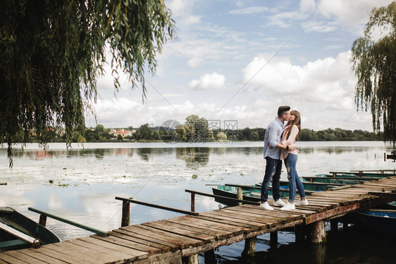 年轻情侣在木桥上拥抱亲吻图片