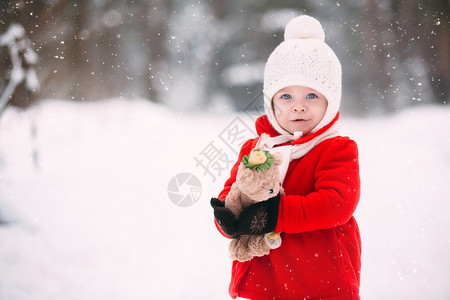 穿着红大衣的小女孩和一只泰迪熊在冬天玩得开心女孩在雪地玩耍女孩在冬天玩得开心图片