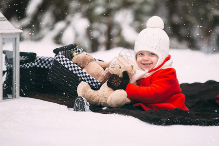 穿红色大衣的女孩在雪地里玩泰迪熊图片