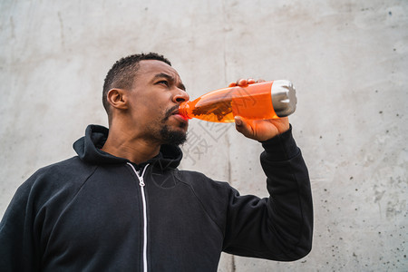 一个运动员在训练后喝东西的肖像在灰色背景运动和健康生活方式下图片