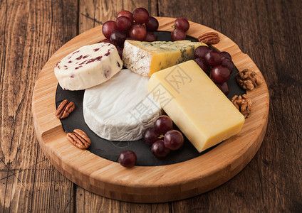 板上的各种奶酪和木制桌底的葡萄图片