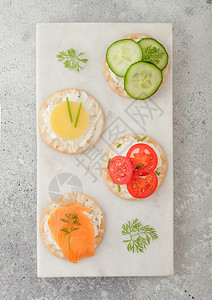 各种圆形健康饼干有鲑鱼和奶酪西红柿黄瓜在光桌背景的大理石板上图片