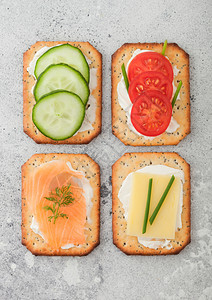 各种健康的饼干有鲑鱼和奶酪西红柿黄瓜放在轻便厨房桌底背景上图片