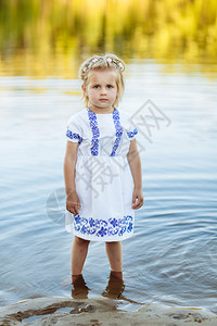 一个小女孩的肖像她穿着白色衣服站在水里夏天的海滩图片