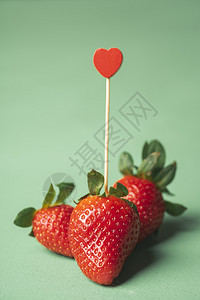 美味的成熟草莓和绿色背景的心形牙签情人节的概念草莓爱甜夏天水果图片