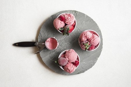 灰色圆盘上碗里自制的草莓冰淇淋上面有浆果冰淇淋和冻水果红色淇淋勺夏季甜点图片