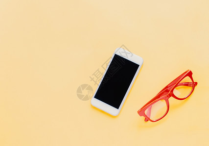 具有智能手机和红色眼镜的生活方式用品平板以亮黄色背景时装风格和夏季为蓝黄色背景的智能手机和红色眼镜图片