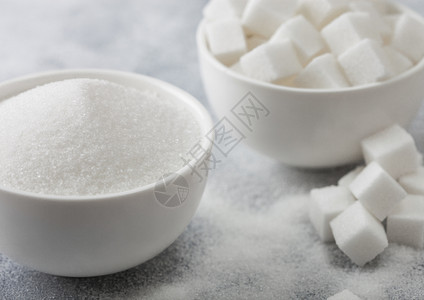 天然白糖立方体和浅底精制糖的白色碗盘图片