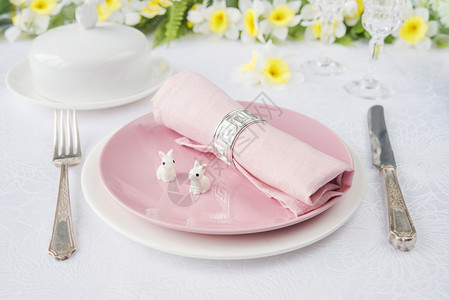 以白色和粉瓷板红餐巾银具两只复活兔子和春花为首的复活节晚宴背景图片