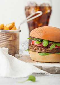 健康素食免费肉汉堡在圆环切肉板上蔬菜在浅底背景土豆杂草和可乐杯图片