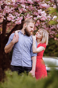 美丽的年轻夫妇有胡子的男人和金发女拥抱在春天公园里图片