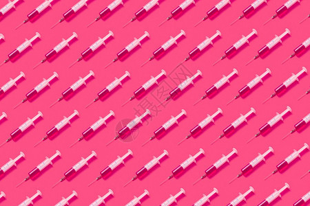 来自无菌的一次塑料针头的横向保健模式其中含有粉红色液体或疫苗其背景是粉红色的热其阴影是软的平原药样来自注射针头其中含有粉红色药物图片