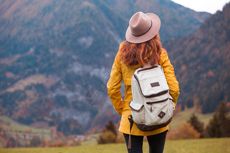 戴着帽子的女孩背着包站在山上的草地图片