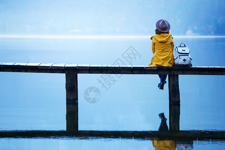 女人坐在湖边的木桥上图片