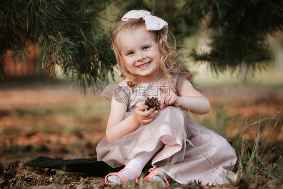 小女孩坐在树下玩松果图片