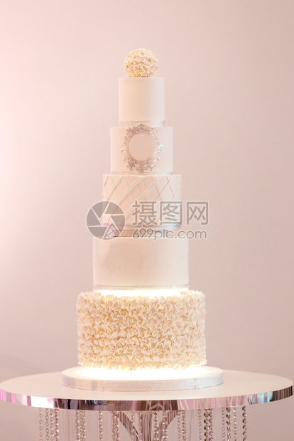 一个白色的大型皇家蛋糕在豪华婚礼上装饰银子细节和白奶油新娘和郎的节庆晚宴后甜点选择焦图片