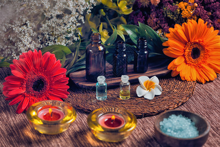 装满浅蓝色和绿基本油的瓶子芳香疗法成分木碗中的蓝海盐红橙和白花装饰芳香疗法的放松概念图片