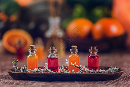 木板上装满红和橙色基本油的瓶子新鲜柑橘水果切成两半图片