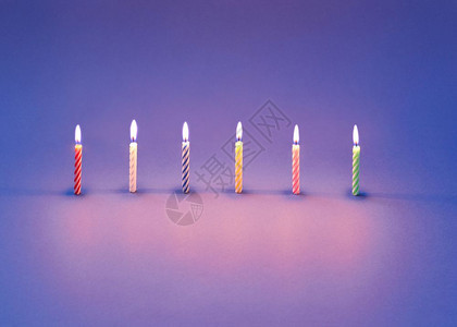在紫罗兰背景上烧蜡烛作为甜点和蛋糕的贺卡有光反射和柔软的影子复制空间图片