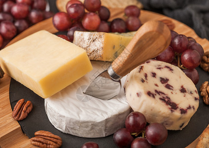 板上的各种奶酪和木本底的葡萄蓝色stilon红色的李斯特脆奶酪和坚果图片