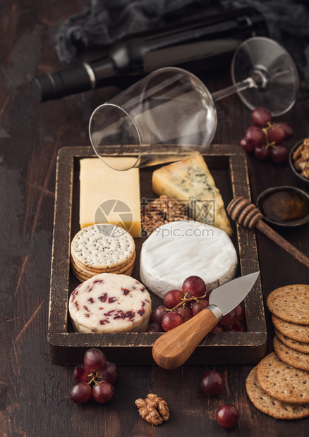 玻璃红葡萄酒和一瓶在木箱和底的葡萄中选取各种奶酪图片