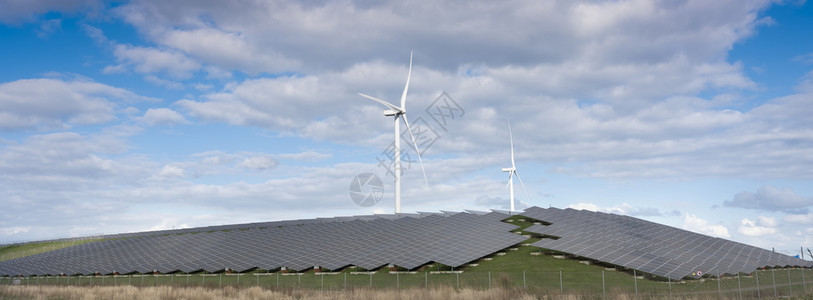 风涡轮机和太阳能电池板形成在蓝色天空下有云层的内河地带替代诱导植物图片