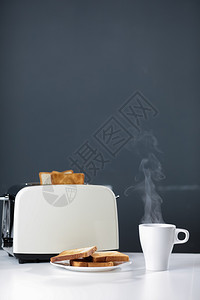 白杯热咖啡或茶和烤面包机在厨房桌边灰色背景的厨房桌上有美味的烤面包片早上餐有选择焦点复制空间白杯热咖啡或茶烤面包机复制空间图片