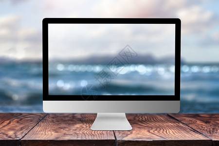 在木制桌子上用海模糊的图像监视器背景与bokeh相同复制空间在海面自然办公室外概念上远程工作计算机显示海面背景模糊图片