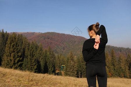 运动女青年在山上做自然伸展练习运动女青年在腿上做瑜伽美丽的森林景观青年女在山上做自然伸展练习图片