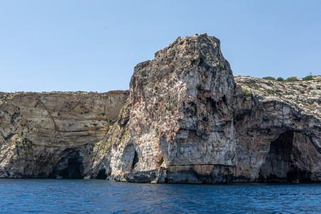 靠近克里特岛海岸的中岩石沉积在海中岩石岸背景的山坡海与地观海照片图片