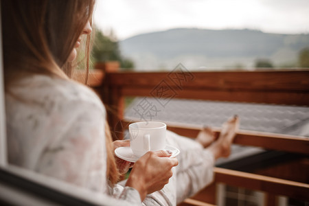穿着睡衣的年轻女子早上在阳台喝咖啡或茶图片