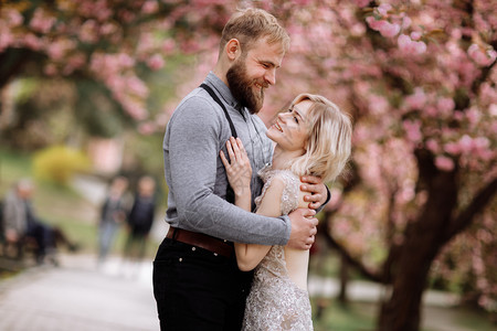 相爱的夫妻在公园的樱花树下拥抱约会图片