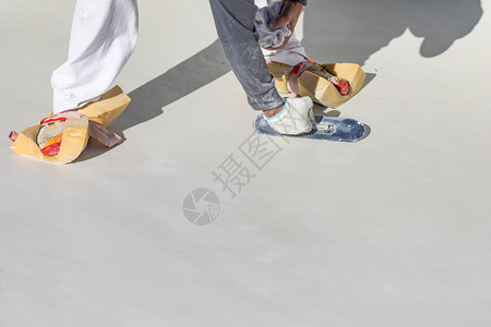 工人穿着海绵在鞋上湿滑的泳池石膏和粗糙图片