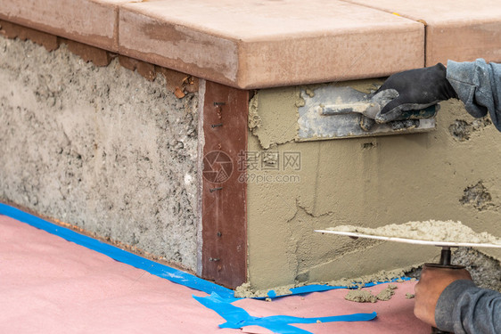 瓷砖工人在池塘建筑地用水泥加土筋图片