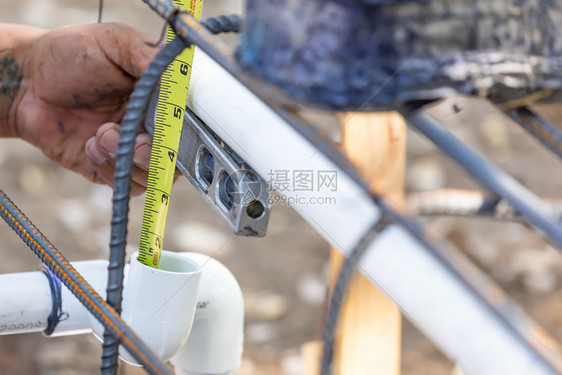 在建筑工地安装pvc管道时使用水工平面和磁带测量装置图片