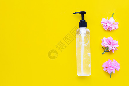 水泵瓶中净化剂凝胶黄底有粉红色康乃馨花手卫生冠状保护概念图片