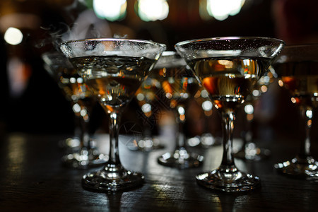 马提尼眼镜站在木架上马提尼眼镜在酒吧上干净的杯子有酒精选择聚焦点马提尼眼镜站在木架上马提尼眼镜在酒吧上清洁的杯子有酒精选择聚焦点图片