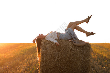 夏季收获的麦田干草卷上漂亮女孩肖像选择焦点图片