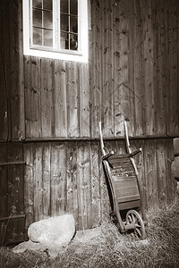 农场墙上的旧木制手推车黑白摄影特写图片