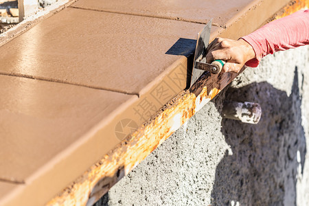 建筑工人在湿水泥上使用不锈钢边缘器在新的池子周围形成应对能力图片