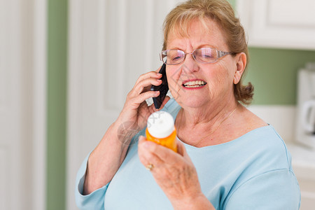 持有处方药瓶的手机上成年老妇女图片