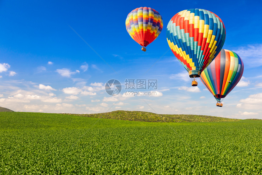 风平浪静的绿地和蓝天上充斥着热气球图片