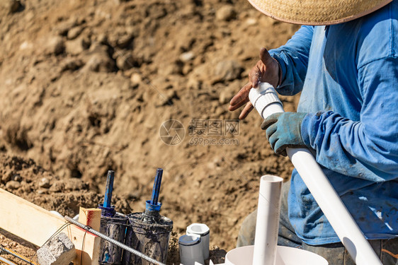 水管工在建筑地对pvc管道施用胶水图片