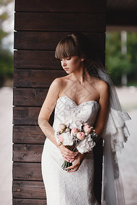 美丽的年轻新娘肖像化妆品和女人的发型白色婚纱和手头白色粉红玫瑰的花束新娘早晨女化妆和发型新娘的早晨图片
